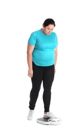 Photo of Overweight woman in sportswear using scales on white background