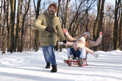 Photo of Happy family having fun with sledge in snowy forest
