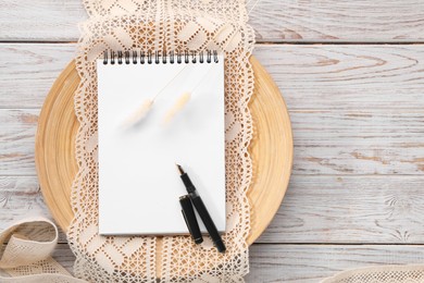 Guest list. Notebook, pen, spikelets and lace ribbons on wooden background, flat lay. Space for text