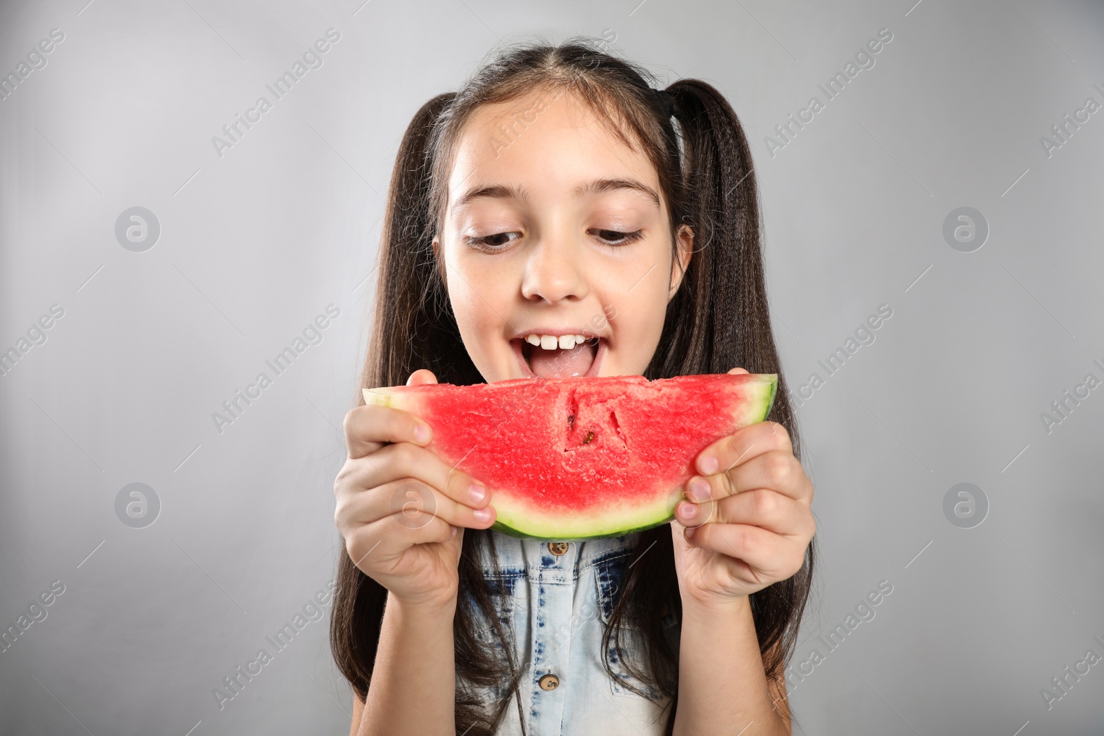 Photo of Cute little girl with watermelon on grey background