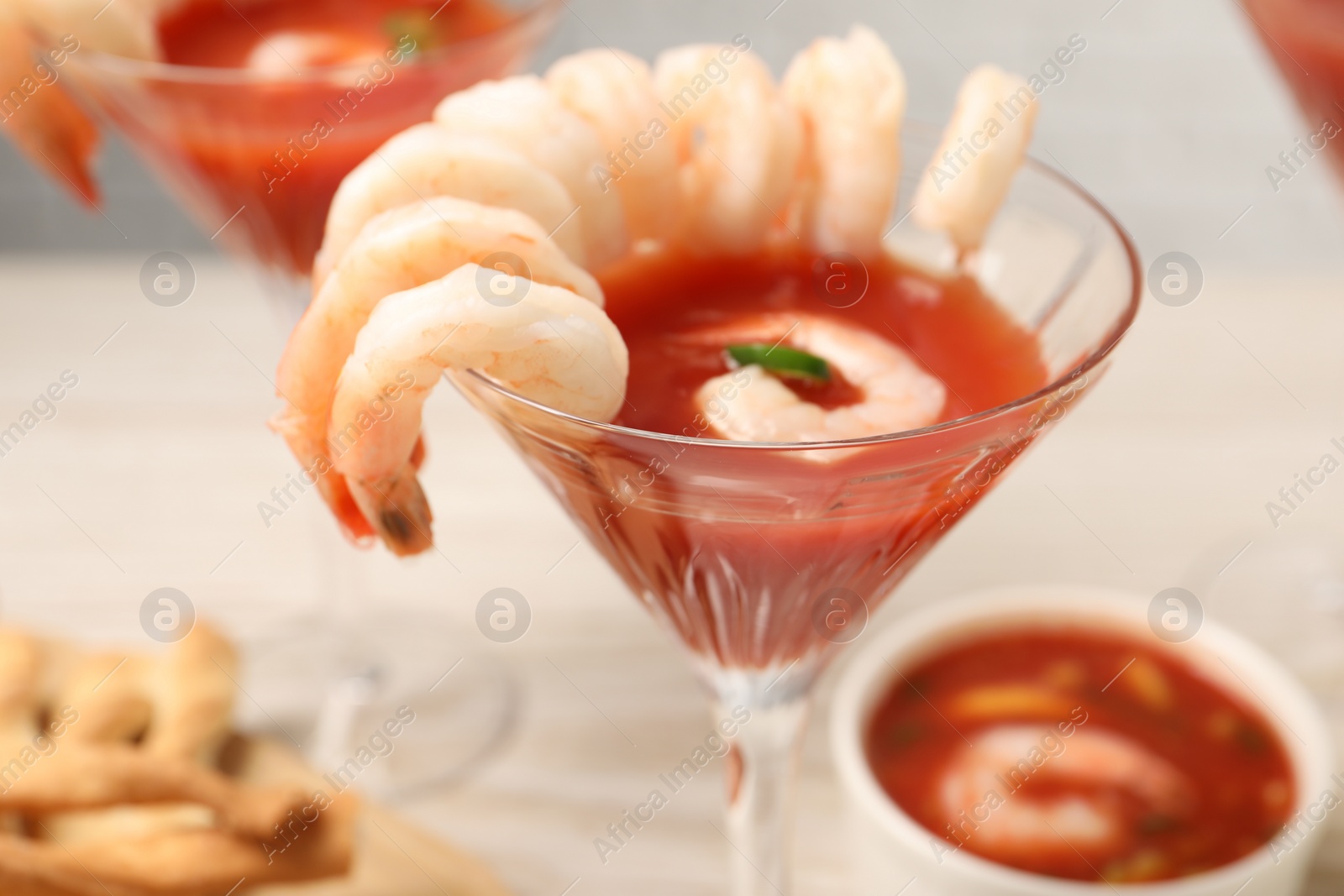 Photo of Tasty shrimp cocktail with sauce in glass on table, closeup