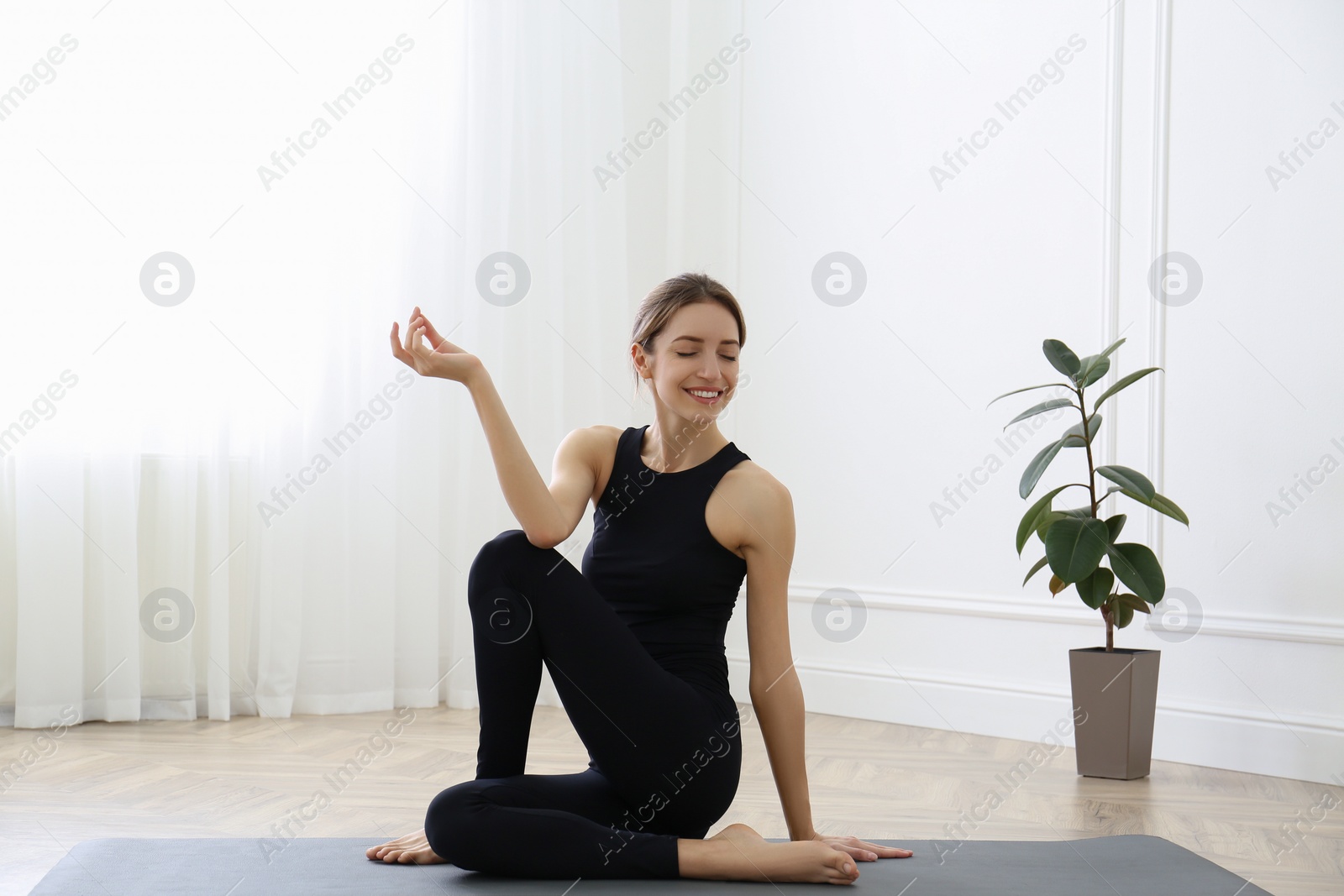 Photo of Young woman practicing half lord of fishes asana in yoga studio. Ardha Matsyendrasana pose