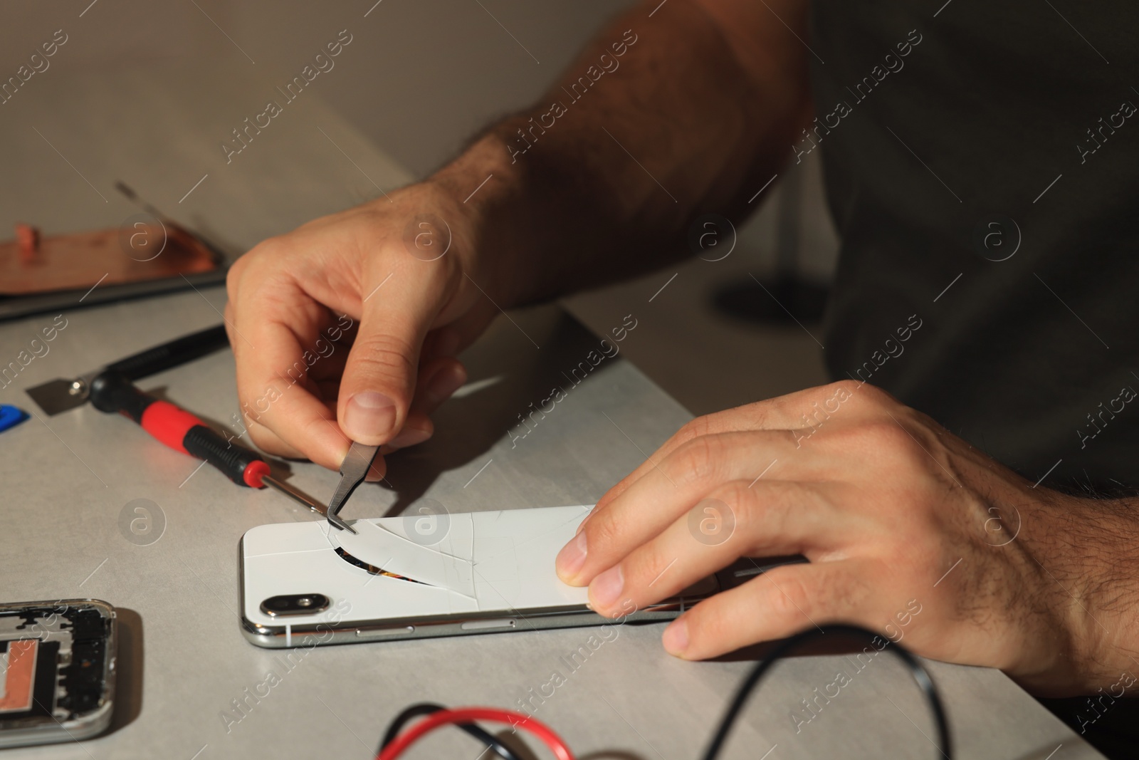 Photo of Technician repairing broken smartphone at table, closeup