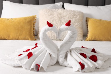 Honeymoon. Swans made with towels and beautiful rose petals on bed