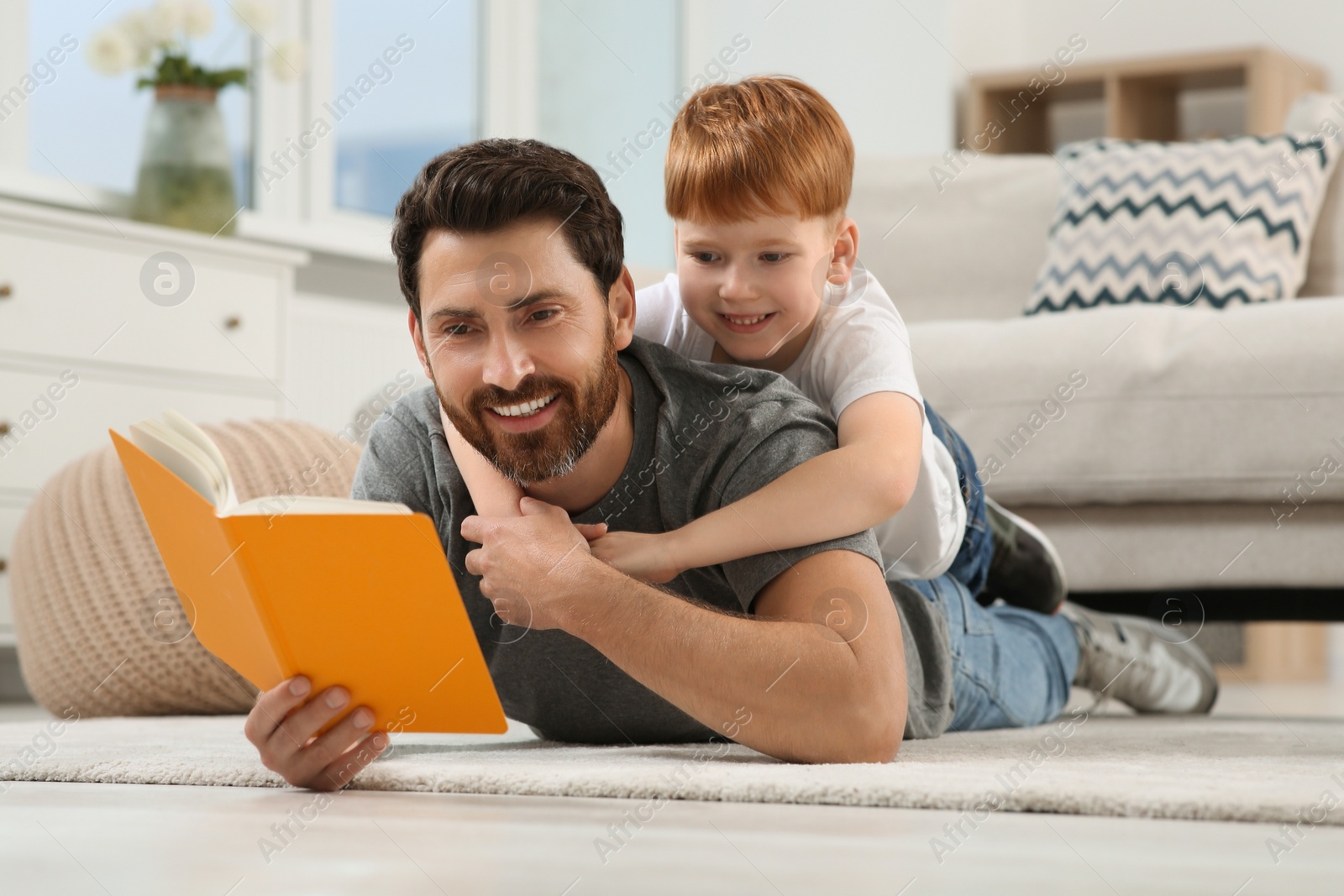 Photo of Father reading book with his child on floor at home