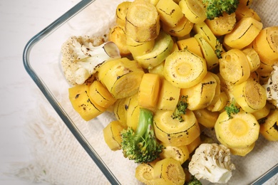 Photo of Baked yellow carrot with broccoli and cauliflowers in glass dish on table, top view