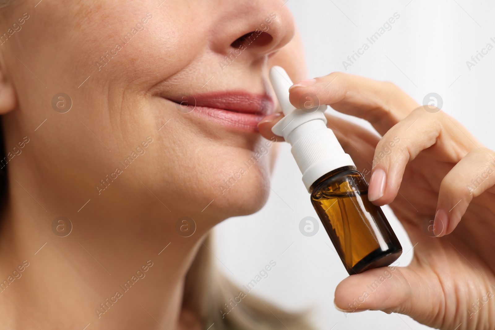 Photo of Medical drops. Woman using nasal spray indoors, closeup