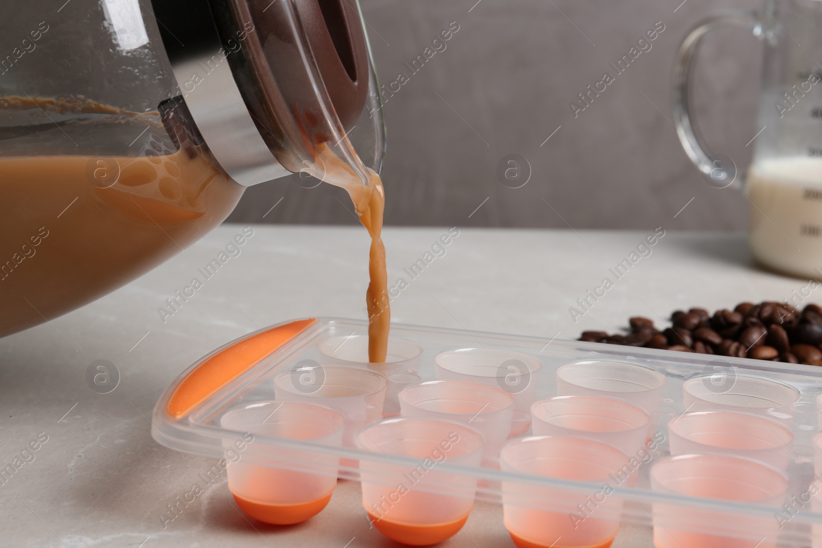 Photo of Pouring coffee drink into ice cube tray on table, closeup