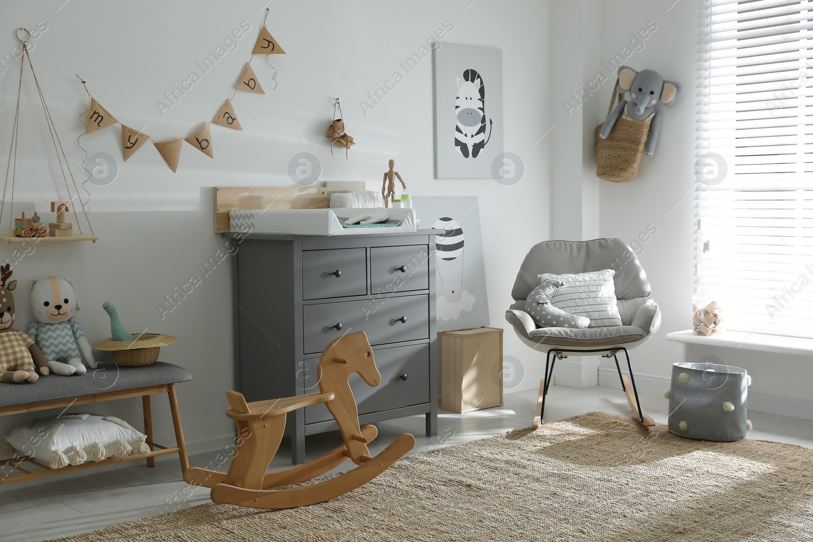 Photo of Beautiful baby room interior with toys, rocking chair and modern changing table