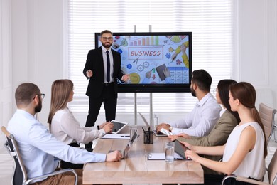 Business trainer near interactive board in meeting room during presentation