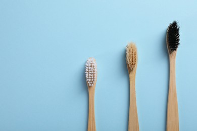 Bamboo toothbrushes on light blue background, flat lay. Space for text