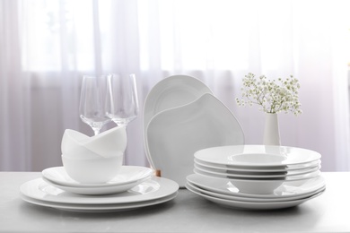 Photo of Set with clean dishes and vase of flowers on light grey table