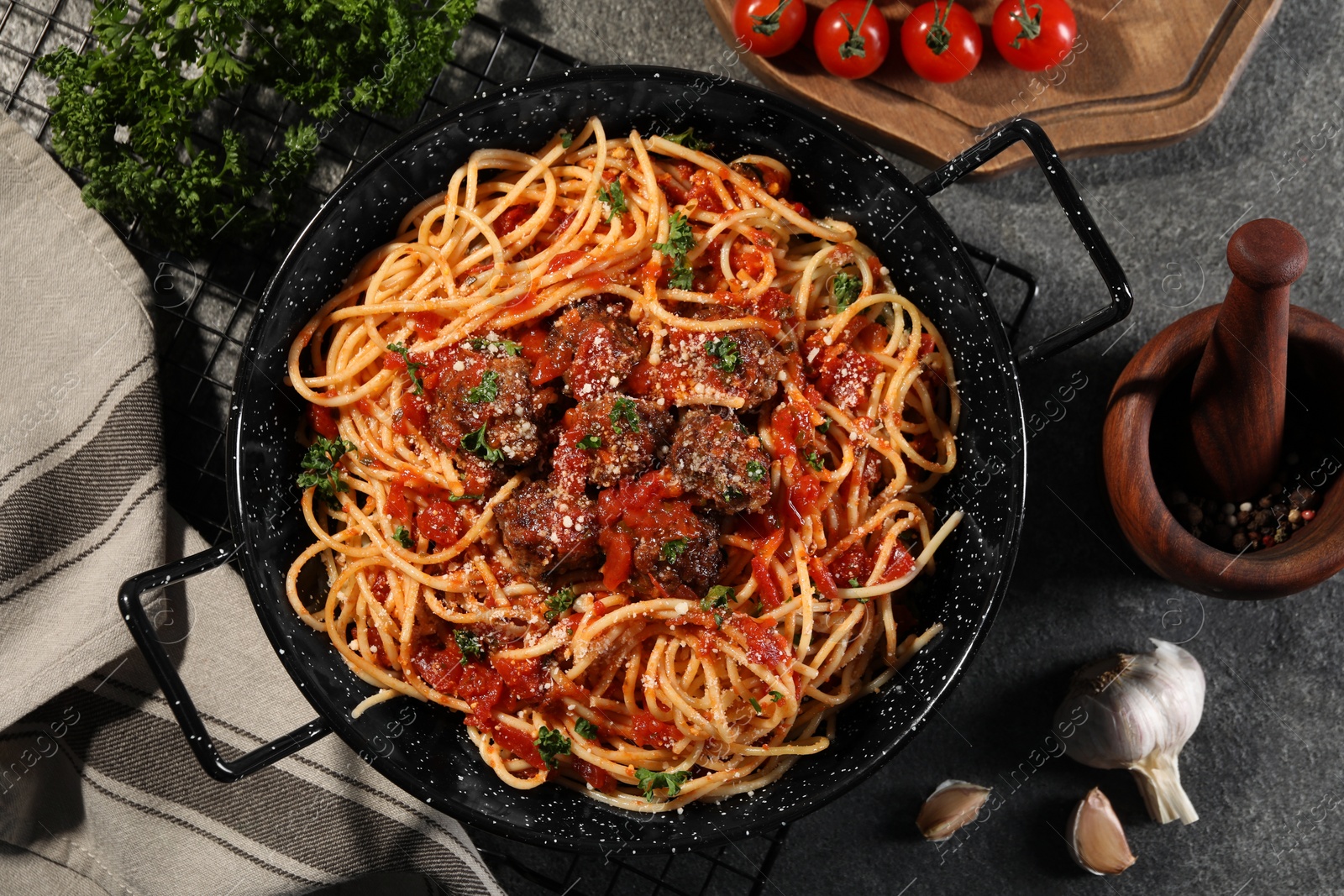 Photo of Delicious pasta with meatballs and tomato sauce near ingredients on grey table, flat lay