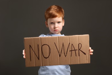 Boy holding poster No War against grey background