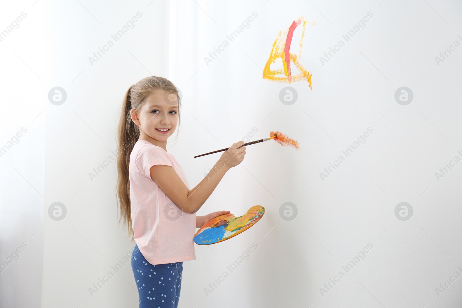 Photo of Little child painting on white wall indoors