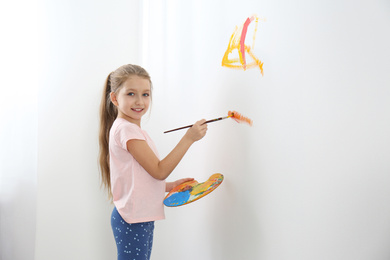 Photo of Little child painting on white wall indoors