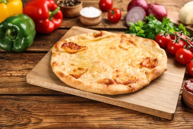 Photo of Delicious khachapuri with cheese and vegetables on wooden table