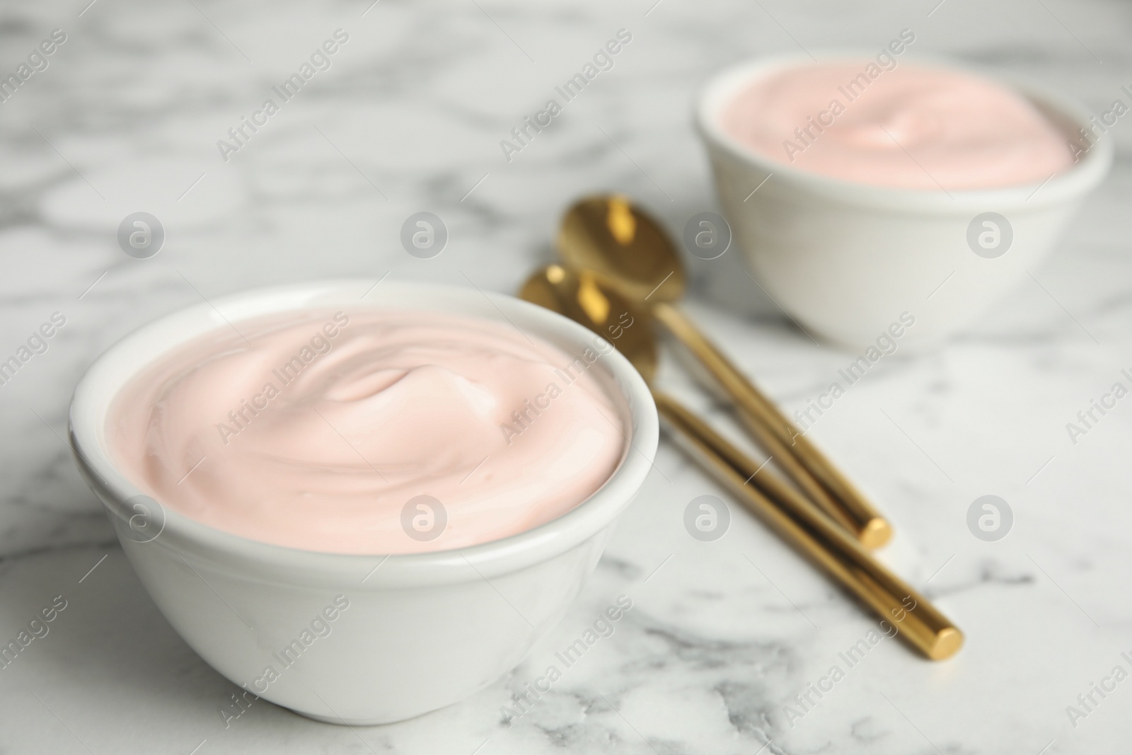 Photo of Tasty organic yogurt on white marble table. Space for text