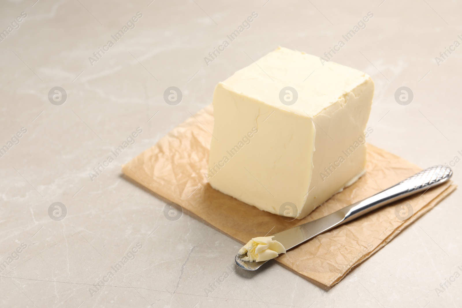 Photo of Block of tasty butter and knife on light table. Space for text