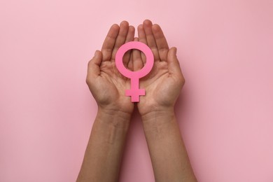 Photo of Woman holding female gender sign on pink background, top view