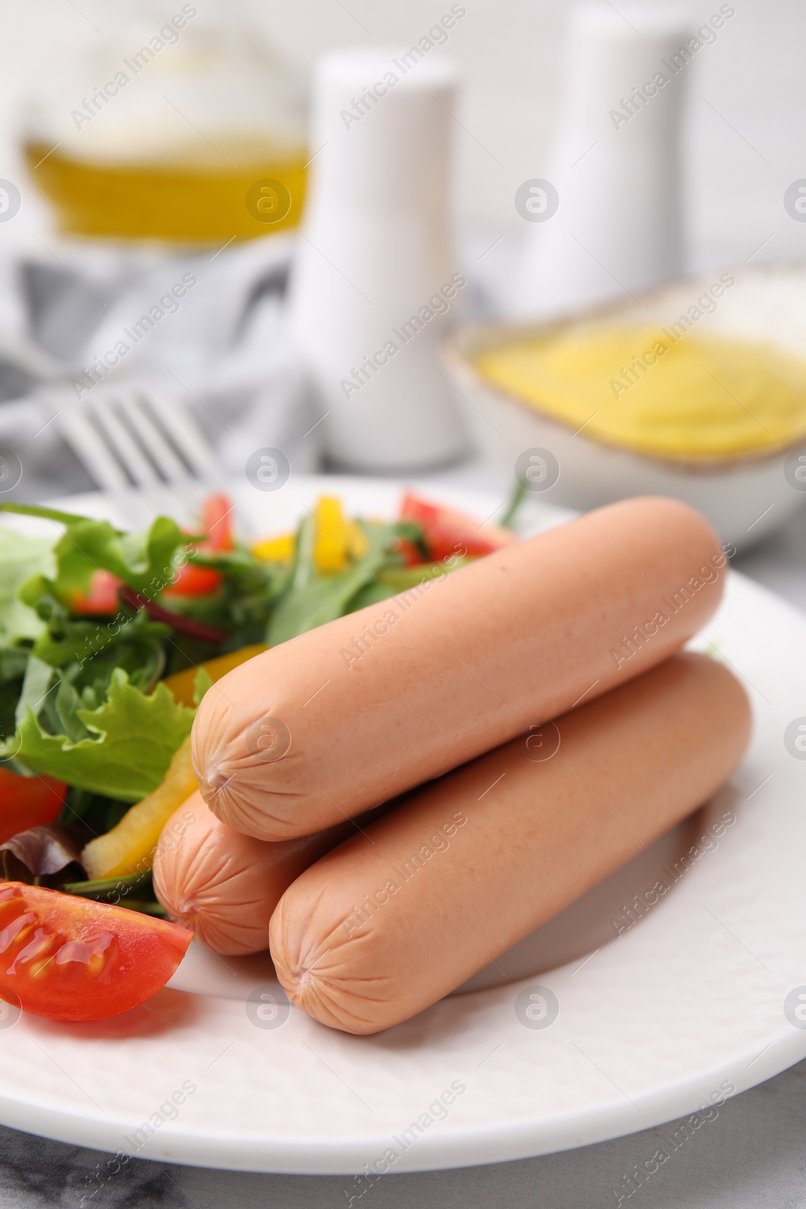 Photo of Delicious boiled sausages with salad on table, closeup