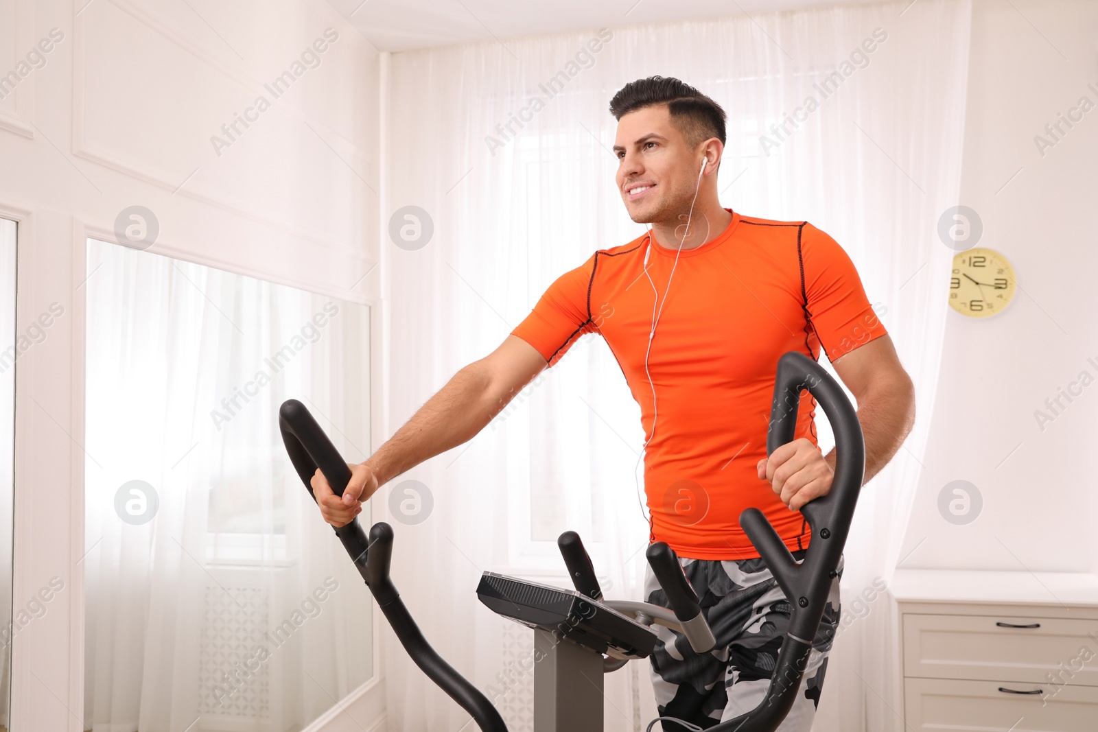 Photo of Man using modern elliptical machine at home