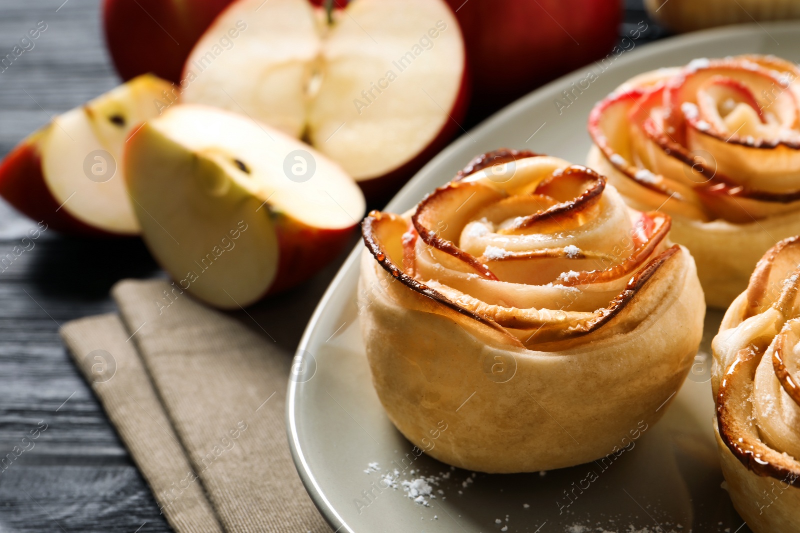 Photo of Freshly baked apple roses on dark wooden table, closeup. Beautiful dessert