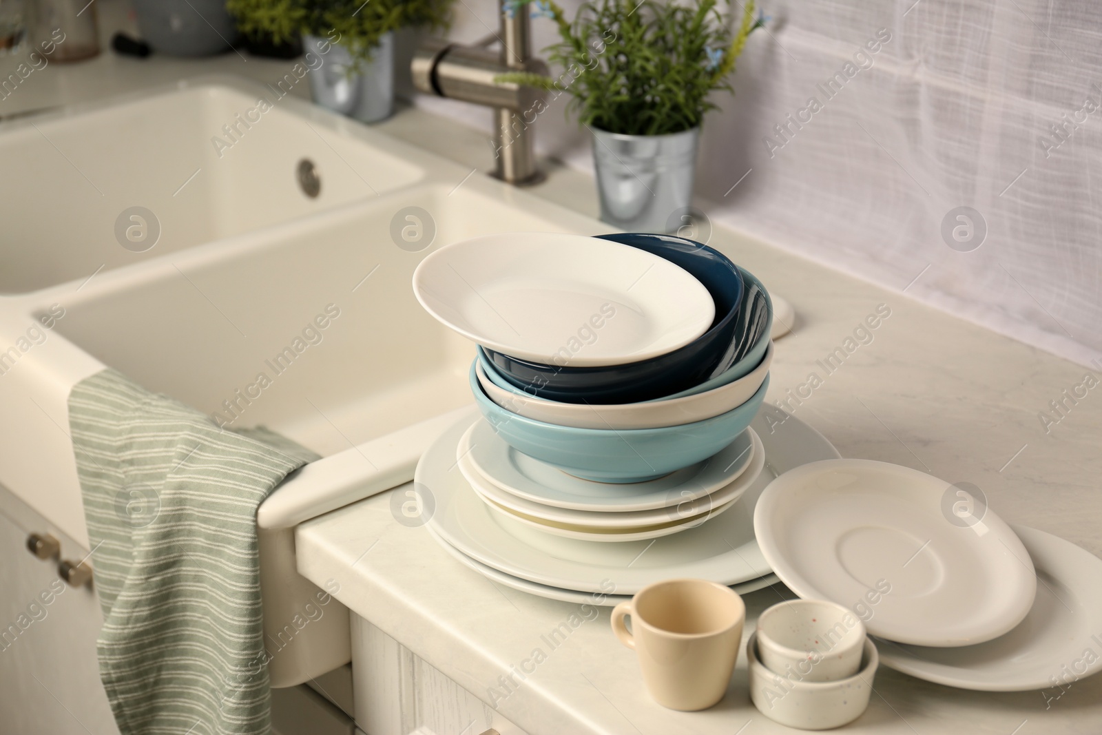 Photo of Set of clean dishware near sink on white countertop in kitchen