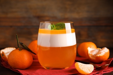 Photo of Delicious tangerine jelly in glass and fresh fruits on table, closeup