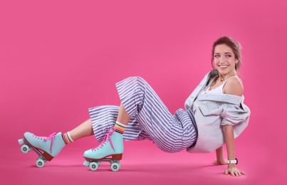 Young woman with retro roller skates on color background