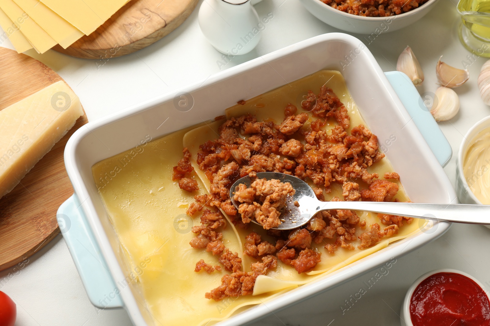 Photo of Cooking lasagna. Pasta sheets and minced meat in baking tray on white table, above view