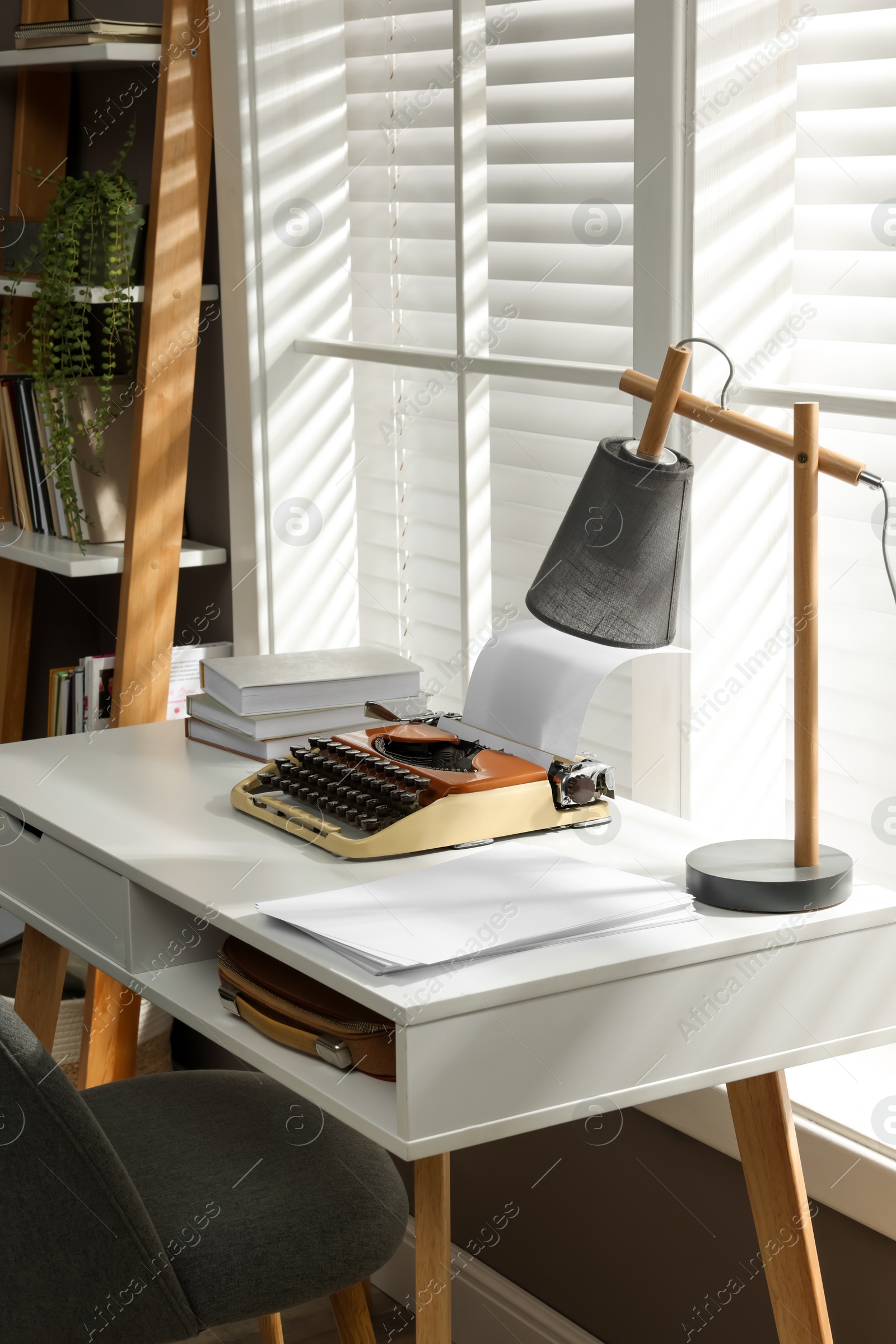 Photo of Comfortable writer's workplace interior with typewriter on desk in front of window