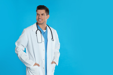 Handsome doctor with stethoscope on blue background. Space for text