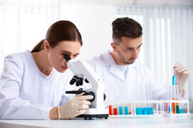 Photo of Scientist with microscope and colleague in laboratory. Medical research