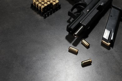 Photo of Handgun, magazine and bullets on grey table. Space for text
