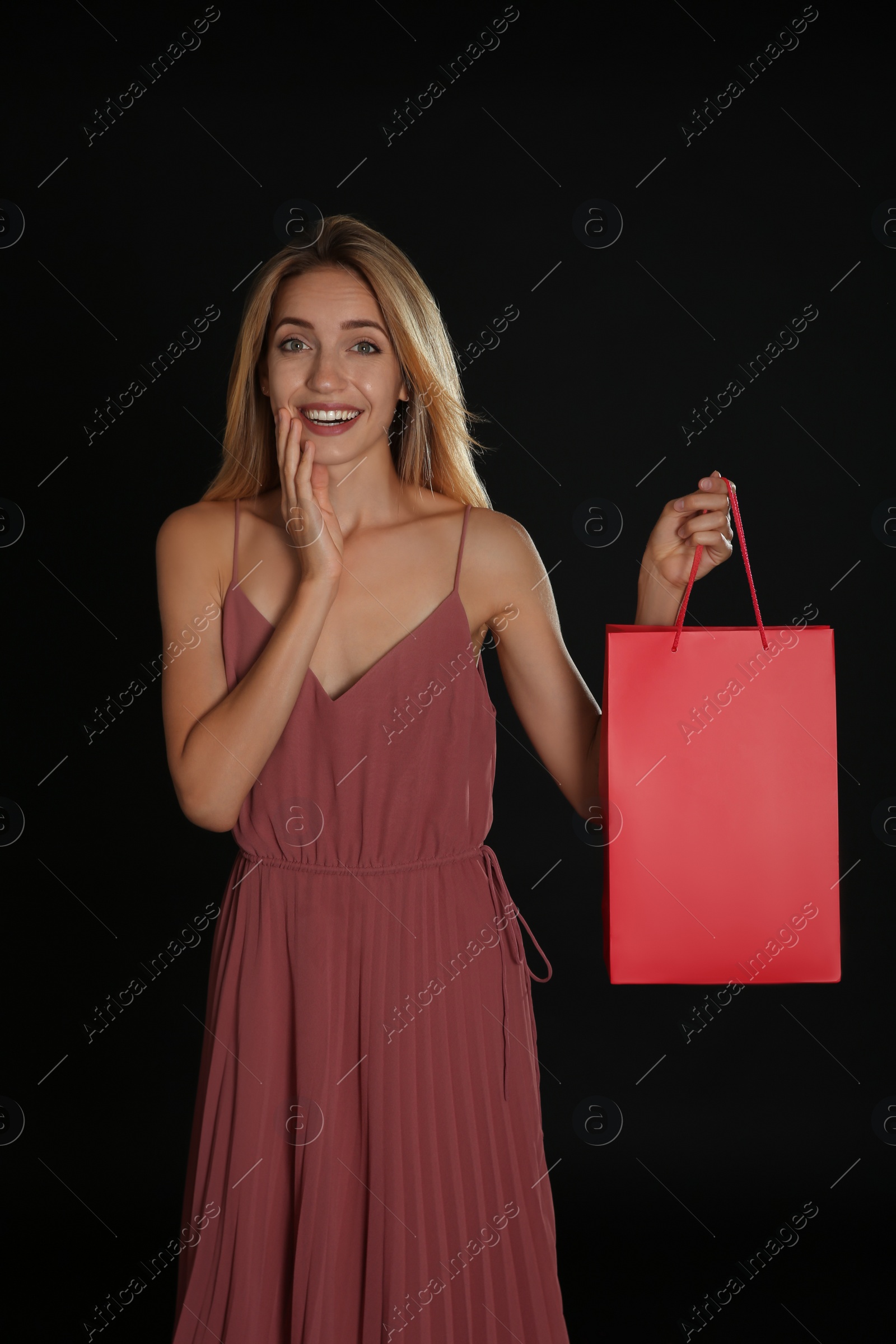 Photo of Happy young woman with shopping bag on dark background. Black Friday Sale