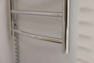 Photo of Heated towel rail on white wall in bathroom, closeup