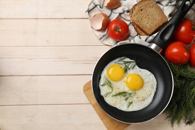 Photo of Frying pan with tasty cooked eggs and other products on light wooden table, flat lay. Space for text