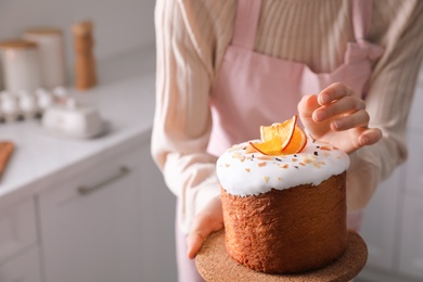 Young woman with traditional decorated Easter cake in kitchen, closeup. Space for text