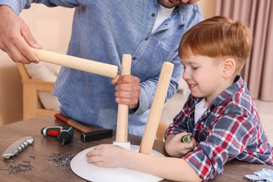 Photo of Father teaching son how to make stool indoors, closeup. Repair work