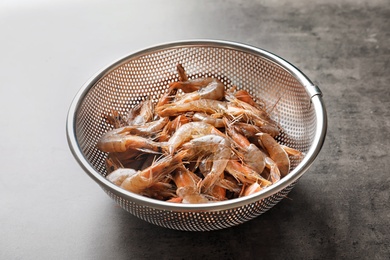 Photo of Colander with fresh shrimps on gray background