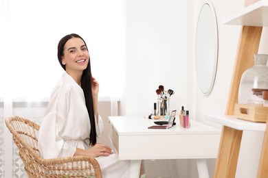 Beautiful young woman at dressing table indoors