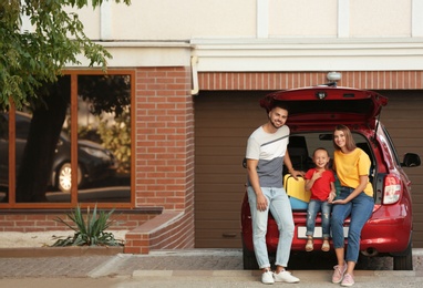 Photo of Happy family near car with open trunk on street