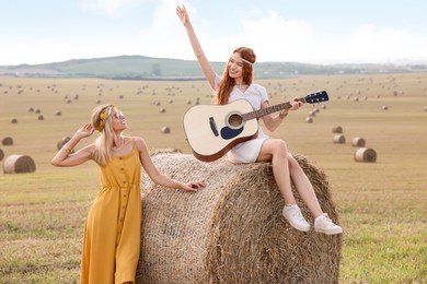 Photo of Beautiful happy hippie women with guitar in field