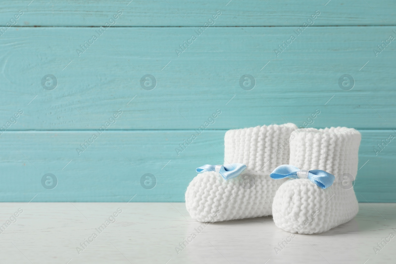 Photo of Handmade baby booties on table against wooden background. Space for text