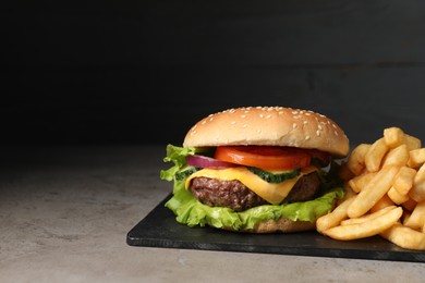 Photo of Delicious burger and french fries served on grey table. Space for text