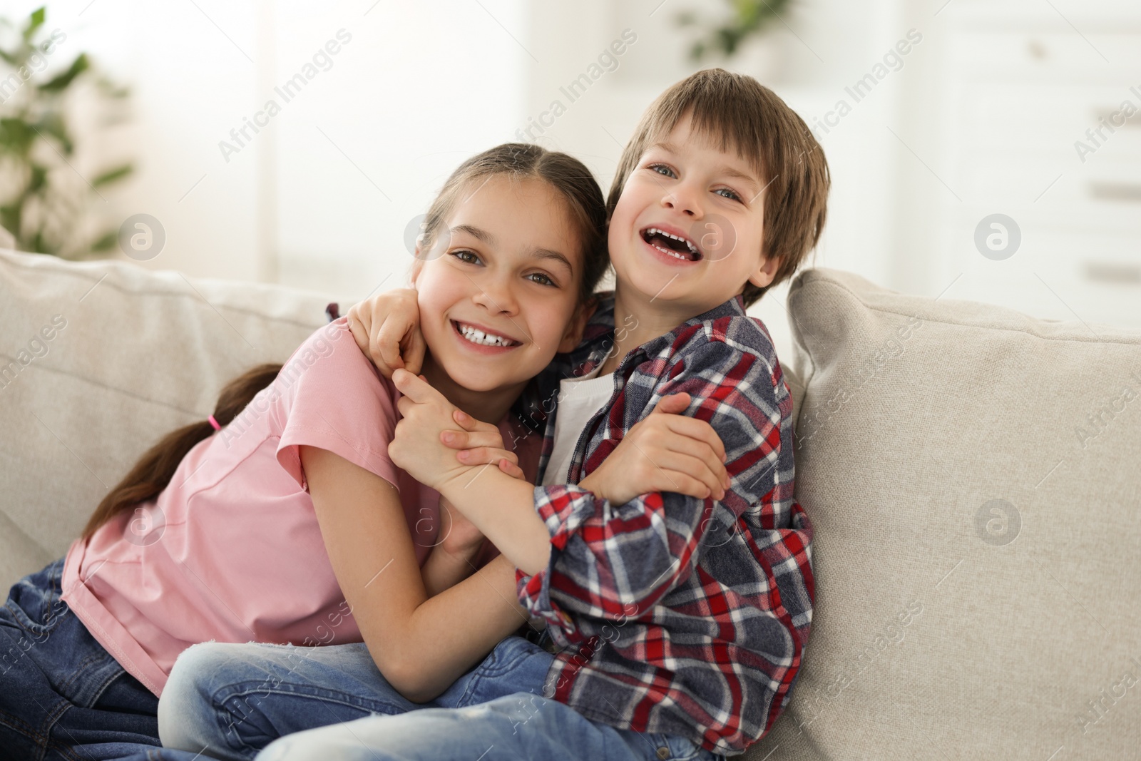 Photo of Happy brother and sister spending time together on sofa at home