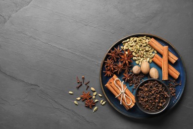 Photo of Dishware with different spices and nuts on gray table, top view. Space for text