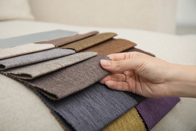 Photo of Woman choosing fabric among colorful samples on beige sofa, closeup