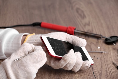 Technician fixing mobile phone at table, closeup. Device repair service